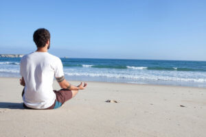 砂浜で座ってで瞑想をする男性